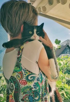 Eine Frau in buntem Kleid mit schwarz-weisser Katze.